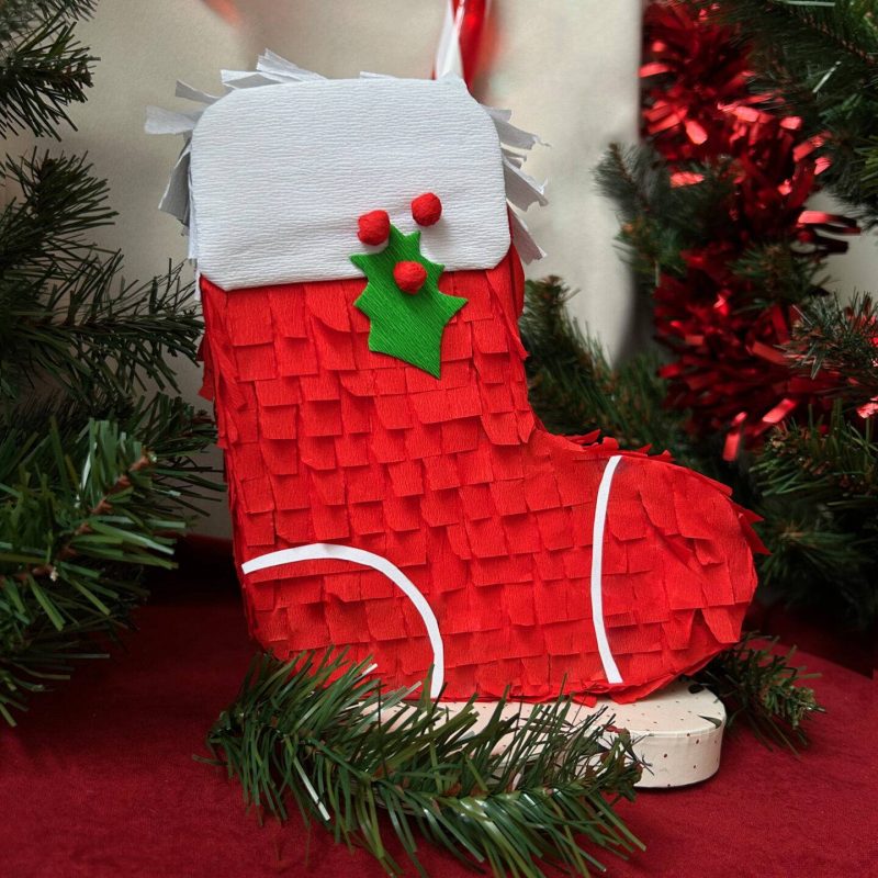 Piñata en forme de chaussette de Noël rouge et blanche inspirée des couleurs du Père Noël."